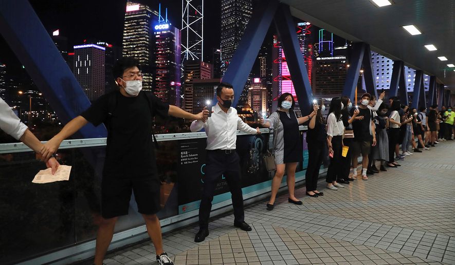 Demonstrators link hands as they gather along an elevated walkway in Hong Kong, Friday, Aug. 23, 2019. Supporters of Hong Kong&#39;s pro-democracy movement created human chains on both sides of the city&#39;s harbor Friday, inspired by a historic protest 30 years ago in the Baltic states against Soviet control. (AP Photo/Kin Cheung)