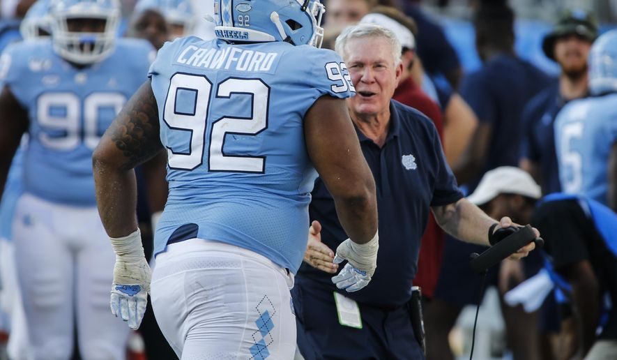 North Carolina head coach Mack Brown, right, greets defensive lineman Aaron Crawford after Crawford sacked South Carolina Gamecocks quarterback Jake Bentley in the second half of an NCAA college football game in Charlotte, N.C., Saturday, Aug. 31, 2019. North Carolina won 24-20. (AP Photo/Nell Redmond)