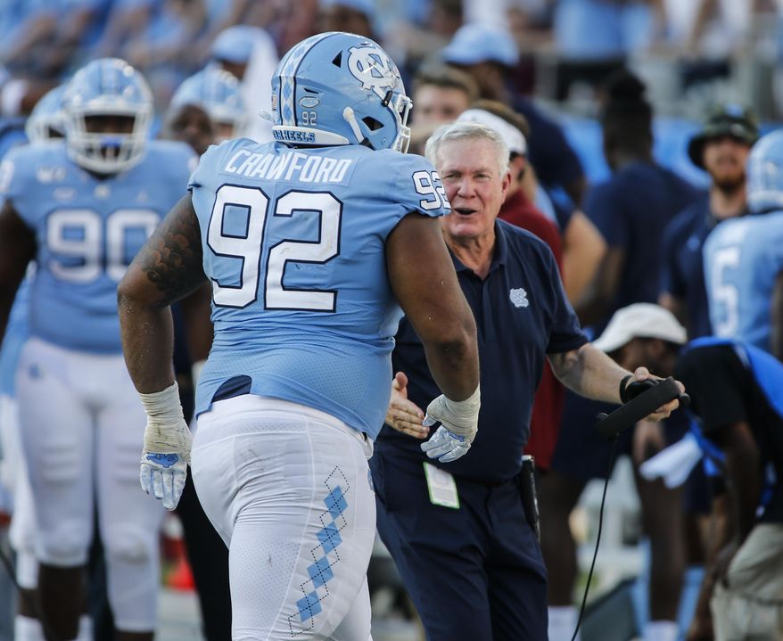 North Carolina head coach Mack Brown, right, greets defensive lineman Aaron Crawford after Crawford sacked South Carolina Gamecocks quarterback Jake Bentley in the second half of an NCAA college football game in Charlotte, N.C., Saturday, Aug. 31, 2019. North Carolina won 24-20. (AP Photo/Nell Redmond)