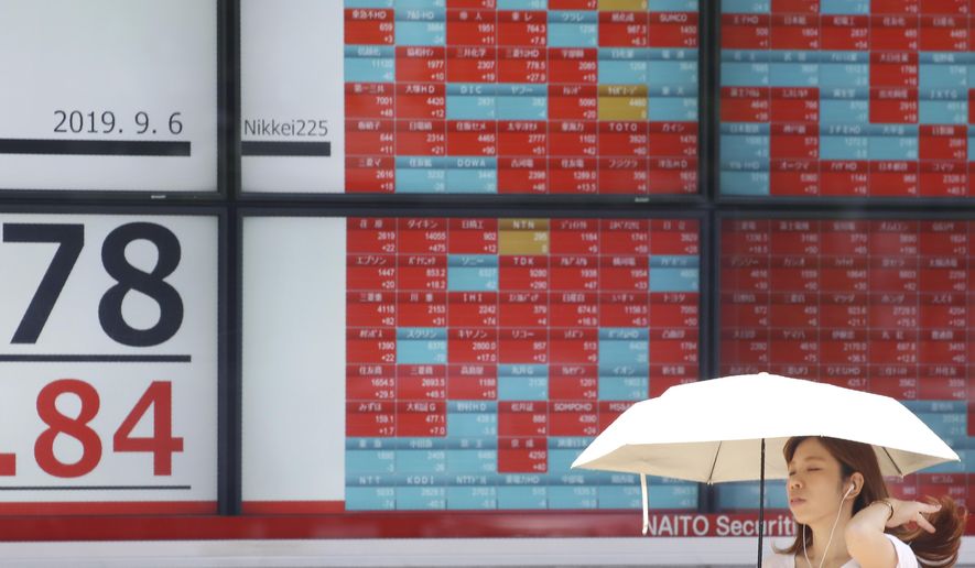 A woman walks by an electronic stock board of a securities firm in Tokyo, Friday, Sept. 6, 2019. Asian shares rose Friday as investors cheered plans for more trade negotiations between Washington and Beijing and drew encouragement from positive data about the U.S. economy. (AP Photo/Koji Sasahara)