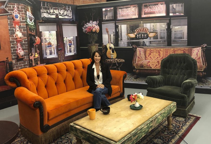 This Sept. 5, 2019 photo shows actress Maggie Wheeler, who played Janice on the NBC sitcom "Friends," posing in a replica of the Central Perk set, at the New York City Pop-Up experience in New York. There are different sections to walk through in 8,500 square feet of loft space, where more than 50 original props from the show are on display. The popular comedy is celebrating its 25th anniversary this year. (AP Photo/Brooke Lefferts)