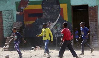 Children play soccer next to a defaced portrait of Former Zimbabwean President Robert Mugabe in Harare, Friday, Sept, 6 2019. Robert Mugabe, the former leader of Zimbabwe forced to resign in 2017 after a 37-year rule whose early promise was eroded by economic turmoil, disputed elections and human rights violations, has died. He was 95. (AP Photo/Tsvangirayi Mukwazhi)