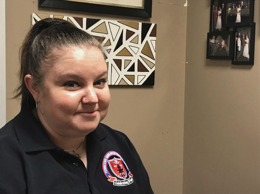 In this Sept. 4, 2019 photo, Jackson Police Department Intelligence Analyst Sarah Webb Jones smiles in front of a piece of art she created with her wedding photos in her office in Jackson, Tenn. Sarah Webb Jones has been working for the Jackson Police Department since 2010, when she joined as an intern with a fresh degree in criminal justice from Middle Tennessee St. (Cassandra Stephenson/The Jackson Sun via AP)