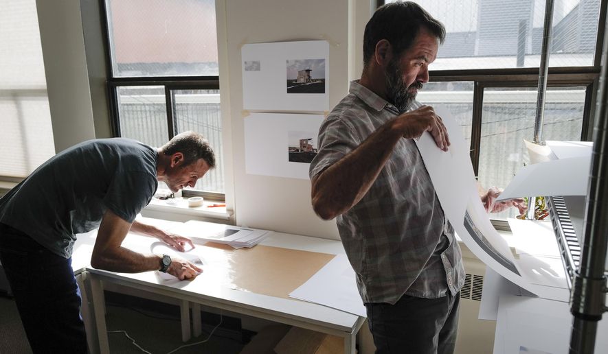 In this photo taken Aug. 21, 2019, Seattle-based photographer Eirik Johnson, left, works with Ben Huff, a local photographer and editor of Ice Fog Press, on a hand-made book of Johnson's photographs titled "Barrow Cabins" in Juneau, Alaska. Johnson's newest photo book isn't for everyone, and that's partially the point of the project. Only a few hundred copies of the book will be made. Each one will be printed, assembled and sewn together by Johnson and Huff. (Michael Penn/The Juneau Empire via AP)