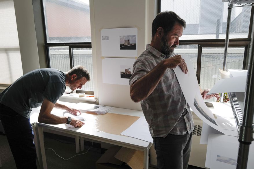 In this photo taken Aug. 21, 2019, Seattle-based photographer Eirik Johnson, left, works with Ben Huff, a local photographer and editor of Ice Fog Press, on a hand-made book of Johnson's photographs titled "Barrow Cabins" in Juneau, Alaska. Johnson's newest photo book isn't for everyone, and that's partially the point of the project. Only a few hundred copies of the book will be made. Each one will be printed, assembled and sewn together by Johnson and Huff. (Michael Penn/The Juneau Empire via AP)