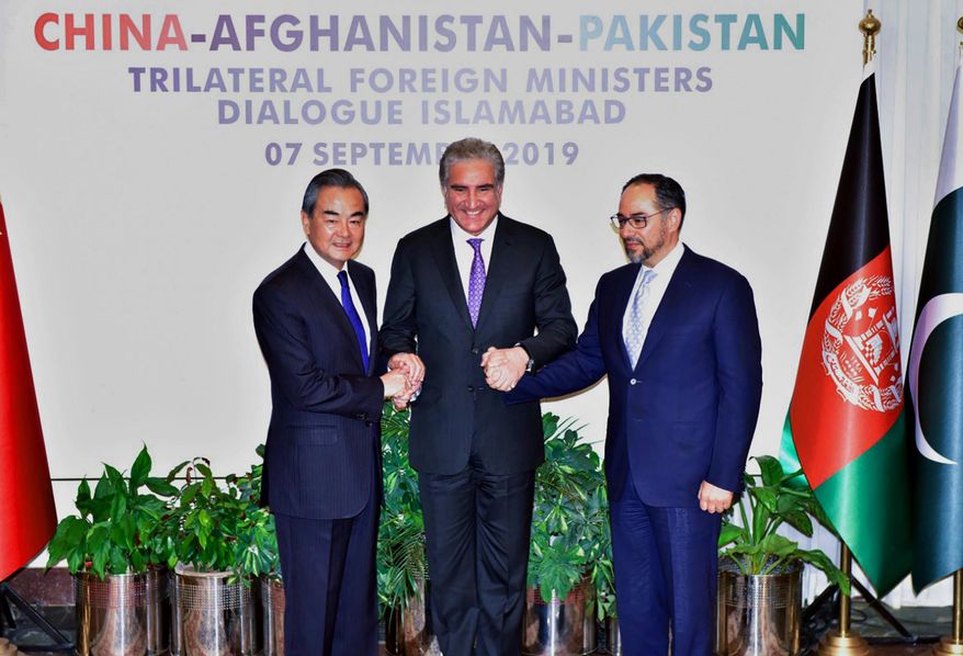 In this photo released by the Press Information Department, Pakistani Foreign Minister Shah Mahmood Qureshi, center, hand shakes jointly with Afghan counterpart Salahuddin Rabbani, right, and Chinese counterpart Wang Yi prior to a meeting in Islamabad, Pakistan, Saturday, Sept, 07, 2019. Pakistan is hosting the third round of trilateral talks with Afghanistan and China to cover trade, counterterrorism and ending Afghanistan's 18-year war. (Press Information Department via AP)