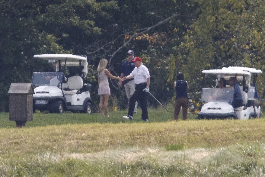President Donald Trump, right, greets an unknown woman, left, during a round of golf at the Trump National Golf Course in Sterling, Va., Sunday, Sept. 8 2019. (AP Photo/ Tom Brenner)