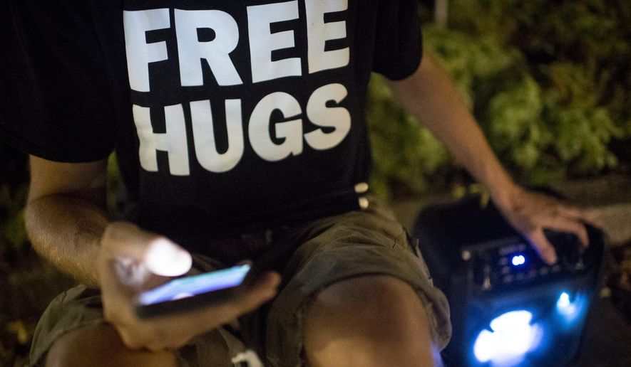 In this Wednesday, Aug. 28, 2019 photo, Scott Schwarz picks a song before performing along Center Street in downtown Provo, Utah. Schwarz often drums along to various popular songs played from his bluetooth speaker. (Isaac Hale/The Daily Herald via AP)