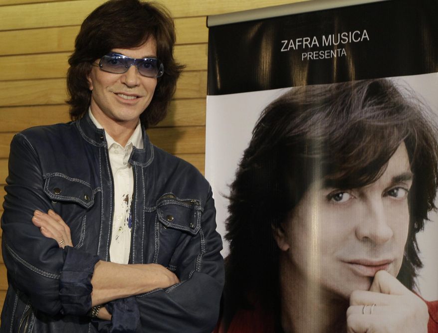 FILE - In this Nov. 4, 2009, file photo, Spanish singer Camilo Sesto poses next to a poster depicting himself during a news conference in Mexico City. Spanish singer and songwriter Camilo Sesto, a popular star in the 1970s and 1980s, has died of heart failure early on Sunday Sept. 8, 2019. He was 72. Sesto, whose real name was Camilo Blanes Cortes, sold more than 100 million records worldwide over his 40-year career. (AP Photo/Gregory Bull, file)