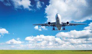 Beautiful airplane. Landscape with big white passenger airplane is flying in the blue sky with clouds over green grass field in summer. Passenger airplane is landing. Commercial plane. Aircraft