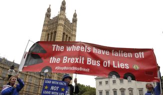 Anti-Brexit campaigner Steve Bray, centre, holds a banner near Parliament in London, Monday, Sept. 9, 2019. British Prime Minister Boris Johnson voiced optimism Monday that a new Brexit deal can be reached so Britain leaves the European Union by Oct. 31. (AP Photo/Kirsty Wigglesworth)