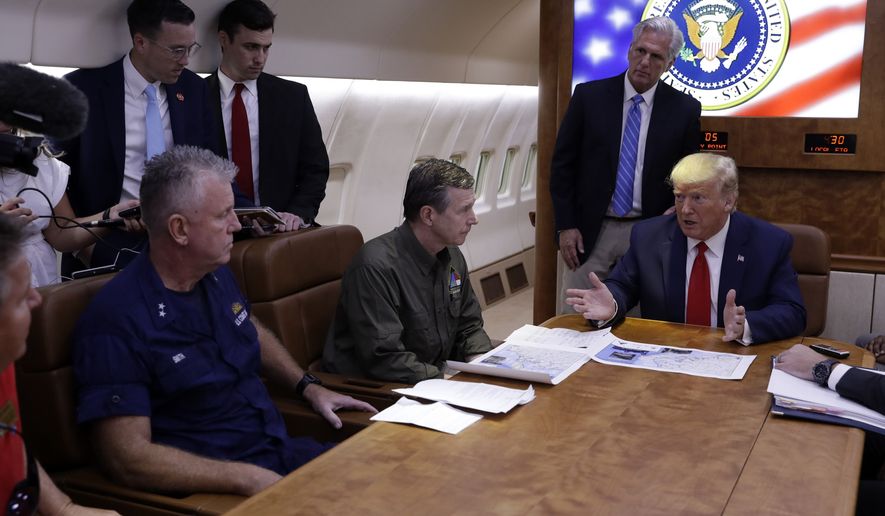 President Donald Trump participates in a briefing with North Carolina Gov. Roy Cooper, left, and House Minority Leader Kevin McCarthy of Calif., center standing, about Hurricane Dorian at Marine Corps Air Station Cherry Point, Monday, Sept. 9, 2019, in Havelock, N.C., aboard Air Force One. (AP Photo/Evan Vucci)