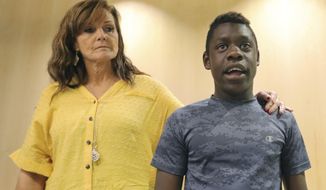 FILE - In this June 7, 2019 file photo, Jerri Hrubes stands next to her son DJ during a news conference in Salt Lake City. Davis County Attorney Troy Rawlings recently confirmed his office is seeking more information from state investigators after an officer pulled his gun on 10-year-old Hrubes in June. (AP Photo/Rick Bowmer, File)