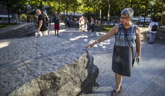 In this Thursday, Aug. 29, 2019, photo a visitor touches one of the granite slabs at the 9/11 Memorial Glade at the National September 11 Memorial &amp;amp; Museum in New York. When the names of nearly 3,000 Sept. 11 victims are read aloud Wednesday, Sept. 11 at the World Trade Center, a half-dozen stacks of stone will quietly salute an untold number of people who aren’t on the list. The granite slabs were installed on the memorial plaza this spring. They recognize an initially unseen toll of the 2001 terrorist attacks: firefighters, police and others who died or fell ill after exposure to toxins unleashed in the wreckage. (AP Photo/Mary Altaffer)