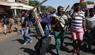 In this photo taken Sunday, Sept. 8, 2019, residents of local hostels march with homemade weapons in Johannesburg. South African police say that two more people have been killed in Johannesburg, bringing to 12 the number of deaths since violence against foreign-owned shops erupted last month. (AP Photo)