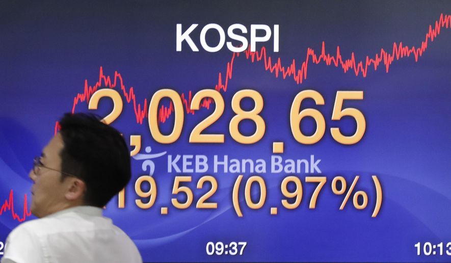 A currency trader walks by the screen showing the Korea Composite Stock Price Index (KOSPI) at the foreign exchange dealing room in Seoul, South Korea, Monday, Sept. 9, 2019. (AP Photo/Lee Jin-man)