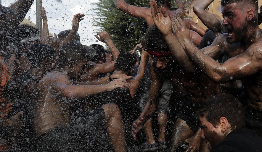 In this photo taken on Friday, Sept. 6, 2019, people painted with black grease celebrate during the traditional festivities of the Cascamorras festival in Baza, Spain. During the Cascamorras Festival, and according to an ancient tradition, participants throw black paint over each other for several hours every September 6 in the small town of Baza, in the southern province of Granada. The "Cascamorras" represents a thief who attempted to steal a religious image from a local church. People try to stop him, chasing him and throwing black paint as they run through the streets. (AP Photo/Manu Fernandez)