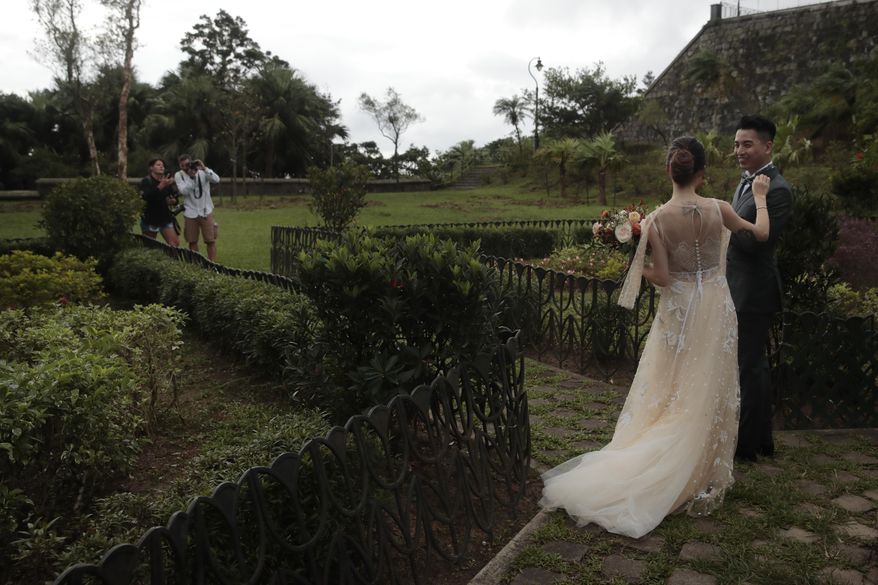 In this Sept. 1, 2019, photo, a bride fixes her groom's bow tie during a wedding photoshoot on the top of the Victoria Peak in Hong Kong. Life is not quite normal after three months of steady protests in the Asian financial center - and yet normal life goes on, as it must, for the city’s 7.4 million residents. (AP Photo/Jae C. Hong)