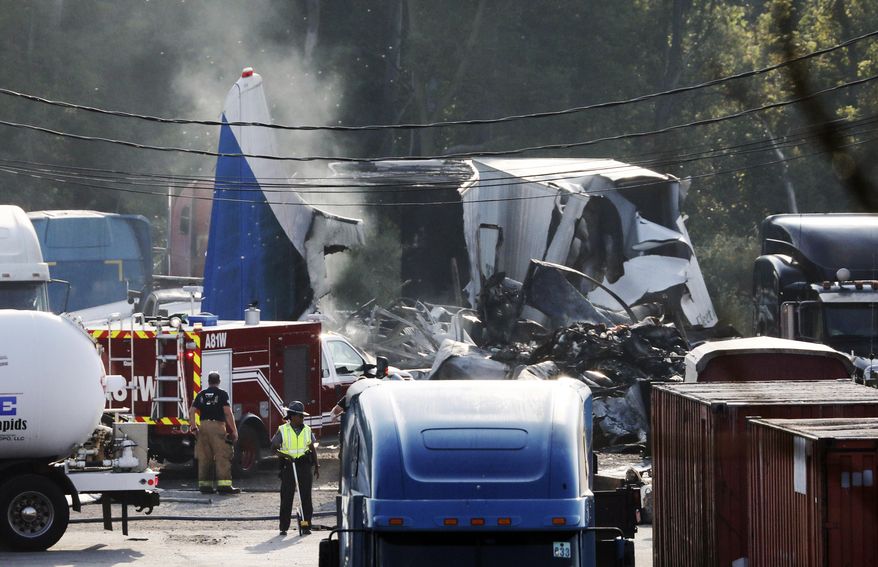 Smoke continue to rise from the wreckage after a small cargo plane crashed at an auto repair business near Toledo Express Airport Wednesday, Sept. 11, 20129, in Monclova, Ohio. The two people who died were aboard the Convair 440, Toledo-Lucas County Port Authority spokeswoman Kayla Lewandowski said. (Dave Zapotosky/The Blade via AP)