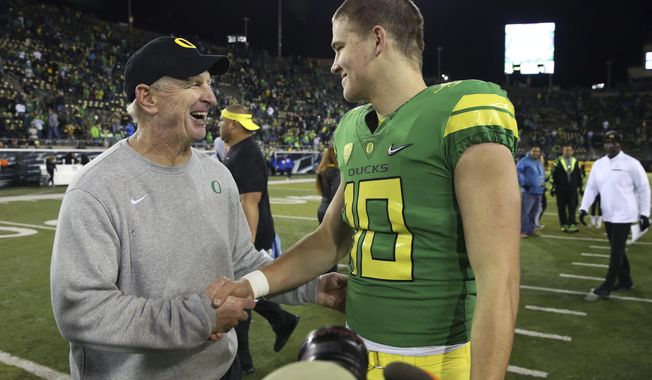FILE - In this Nov. 18, 2017, file photo, Oregon defensive coordinator Jim Leavitt, left, congratulates quarterback Justin Herbert after the team's NCAA college football game against Arizona in Eugene, Ore. Florida State coach Willie Taggart is hiring former Oregon defensive coordinator Leavitt as an analyst to help fix a flailing defense, a person involved with the decision told The Associated Press on Wednesday night, Sept. 11, 2019. The person spoke on condition of anonymity because the hiring was still being finalized. Leavitt worked with Taggart in 2017 during the one season Taggart was head coach at Oregon. (AP Photo/Chris Pietsch, File)