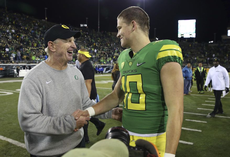 FILE - In this Nov. 18, 2017, file photo, Oregon defensive coordinator Jim Leavitt, left, congratulates quarterback Justin Herbert after the team's NCAA college football game against Arizona in Eugene, Ore. Florida State coach Willie Taggart is hiring former Oregon defensive coordinator Leavitt as an analyst to help fix a flailing defense, a person involved with the decision told The Associated Press on Wednesday night, Sept. 11, 2019. The person spoke on condition of anonymity because the hiring was still being finalized. Leavitt worked with Taggart in 2017 during the one season Taggart was head coach at Oregon. (AP Photo/Chris Pietsch, File)