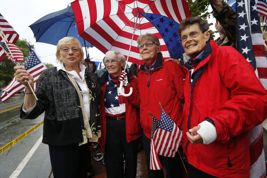 Maine Gov. Janet Mills, far left, shares a moment with the "Freeport flag ladies," left to right, JoAnn Miller, Elaine Greene, and Carmen Footer, on Main Street, Wednesday, Sept. 11, 2019, in Freeport, Maine. The three women who've been waving the Stars and Stripes each week since the 9/11 attacks are retiring the tradition. (AP Photo/Robert F. Bukaty)