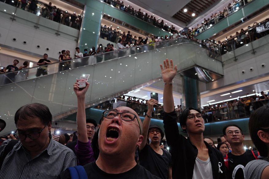 Local residents sing a theme song written by protesters "Glory be to thee" at a shopping mall in Hong Kong Wednesday, Sept. 11, 2019. Hundreds of Hong Kong citizens gathered at several malls late Wednesday, chanting slogans and belting out a new protest song. The song, "glory to Hong Kong", was penned online and has been embraced by protesters as their anthem song. The peaceful mall gatherings marked a respite after violent clashes over the weekend. (AP Photo/Vincent Yu)