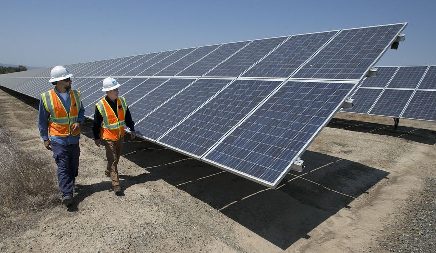 FILE - In this Thursday, Aug. 17, 2017, file photo, solar tech Joshua Valdez, left, and senior plant manager Tim Wisdom walk past solar panels at a Pacific Gas and Electric Solar Plant, in Dixon, Calif. U.S. wholesale prices edged up a slight 0.1% in August 2019 as energy prices took a big plunge, a further sign that inflation is remaining tame. The Labor Department says the gain in its producer price index, which measures inflation pressures before they reach the consumer, followed a modest 0.2% rise in July. Core inflation, which excludes food and energy, was up a stronger 0.3%. (AP Photo/Rich Pedroncelli, File)