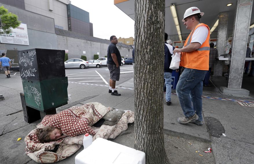 FILE - In this May 24, 2018 file photo, a man sleeps on the sidewalk as people behind line up to buy lunch at a Dick's Drive-In restaurant in Seattle. An elected official in King County, where Seattle is located, wants to dedicate $1 million for one-way bus tickets to relocate homeless people who say they want to reconnect with family outside the region. (AP Photo/Elaine Thompson, File)