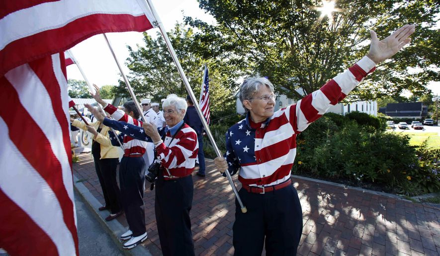 FILE - In this Aug. 23, 2011, file photo, the Freeport Flag Ladies, Carmen Footer, from left, JoAnn Miller and Elaine Greene, wave to vehicles in Freeport, Maine. The three women who've been waving the Stars and Stripes each week since the 9/11 attacks are folding up their flags in Freeport, Maine. The tradition started after the terrorist attacks 18 year ago. (AP Photo/Robert F. Bukaty, File)