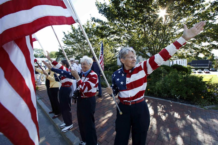 FILE - In this Aug. 23, 2011, file photo, the Freeport Flag Ladies, Carmen Footer, from left, JoAnn Miller and Elaine Greene, wave to vehicles in Freeport, Maine. The three women who've been waving the Stars and Stripes each week since the 9/11 attacks are folding up their flags in Freeport, Maine. The tradition started after the terrorist attacks 18 year ago. (AP Photo/Robert F. Bukaty, File)