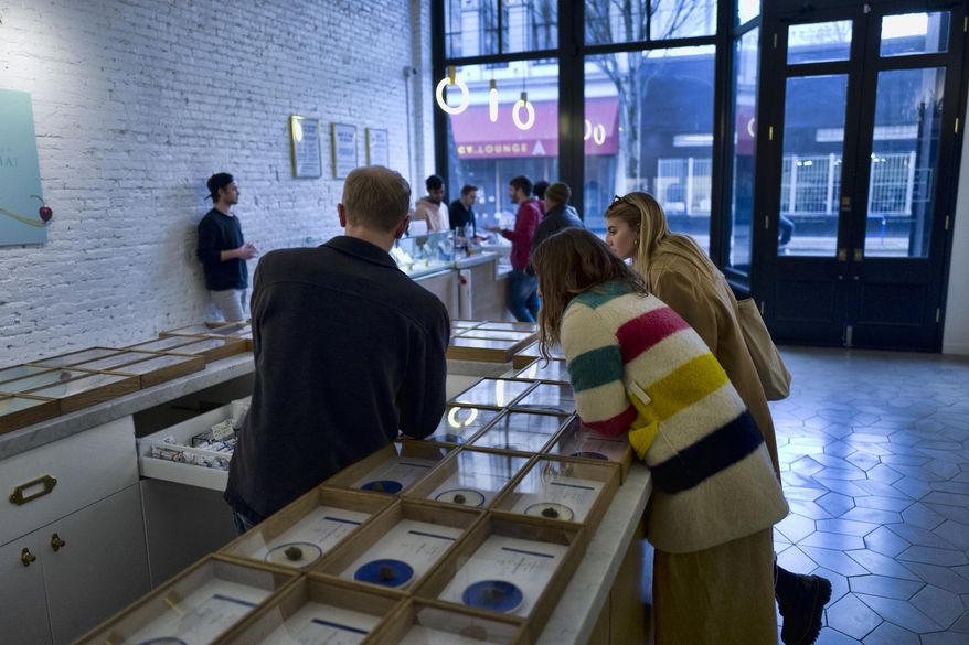 In this Thursday, Feb. 7, 2019, file photo, a bud tender helps customers at a dispensary in Portland, Ore. In the wake of lung illnesses and deaths related to vaping, Oregon will ask its legal marijuana retailers to review the cannabis products on their shelves and voluntarily hold or pull those that they don't feel confident about. (AP Photo/Richard Vogel, File)