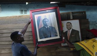 Supporters of Former Zimbabwean President Robert Mugabe place his portrait next to that of Zimbabwean President Emmerson Mnangagwa in Harare, Tuesday, Sept, 10, 2019. Mugabe who died aged 95 in Singapore, is expected to be buried on Sunday according to state media. Zimbabwean President Emmerson Mnangagwa declared him a national hero. (AP Photo/Tsvangirayi Mukwazhi)