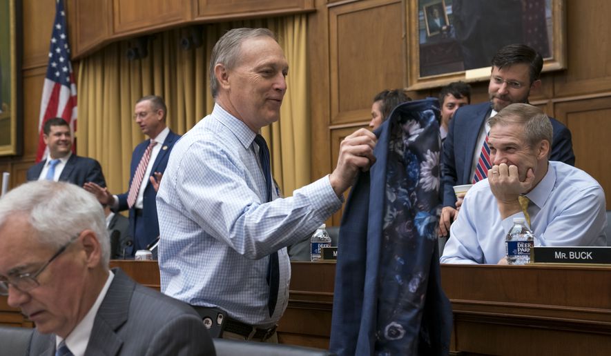 Rep. Andy Biggs, R-Ariz., the newly elected chairman of the conservative House Freedom Caucus, takes off his jacket for the amusement of fellow caucus member Rep. Jim Jordan, R-Ohio, right, as they arrive for the start of a markup session of the House Judiciary Committee as they work on guidelines for impeachment hearings on President Donald Trump, at the Capitol in Washington, Thursday, Sept. 12, 2019. (AP Photo/J. Scott Applewhite)