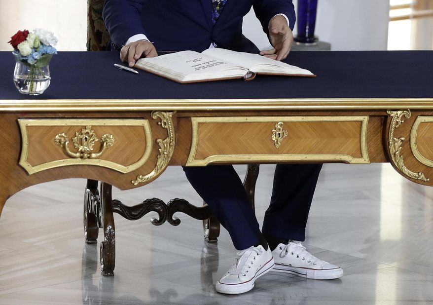Albanian Prime Minister Edi Rama, wearing sport shoes, signs into a book upon his arrival for the V4+West Balkan summit in Prague, Czech Republic, Thursday, Sept. 12, 2019. (AP Photo/Petr David Josek)