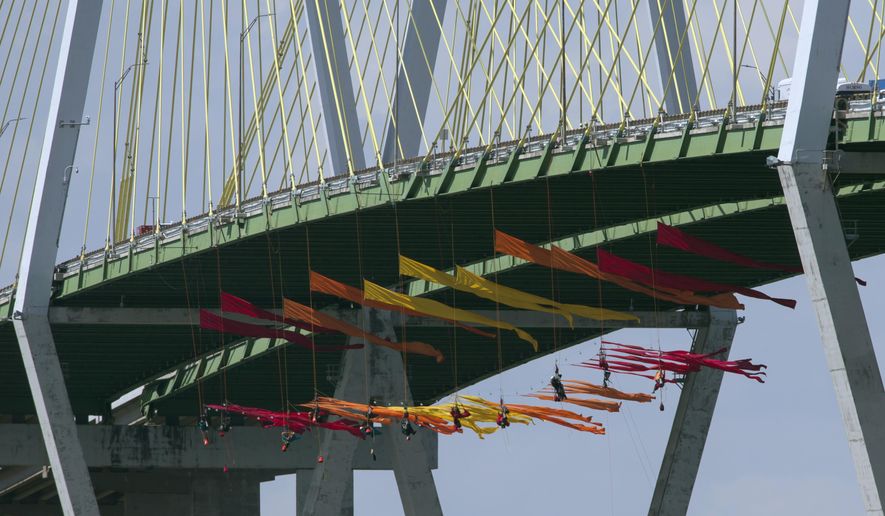 Greenpeace USA protesters dangle from the Fred Hartman Bridge Thursday, Sept. 12, 2019, in Baytown, Texas. A portion of the Houston Ship Channel has closed after about a dozen Greenpeace USA activists protesting the use of fossil fuels suspended themselves from a bridge ahead of a Democratic presidential debate.( Yi-Chin Lee/Houston Chronicle via AP)