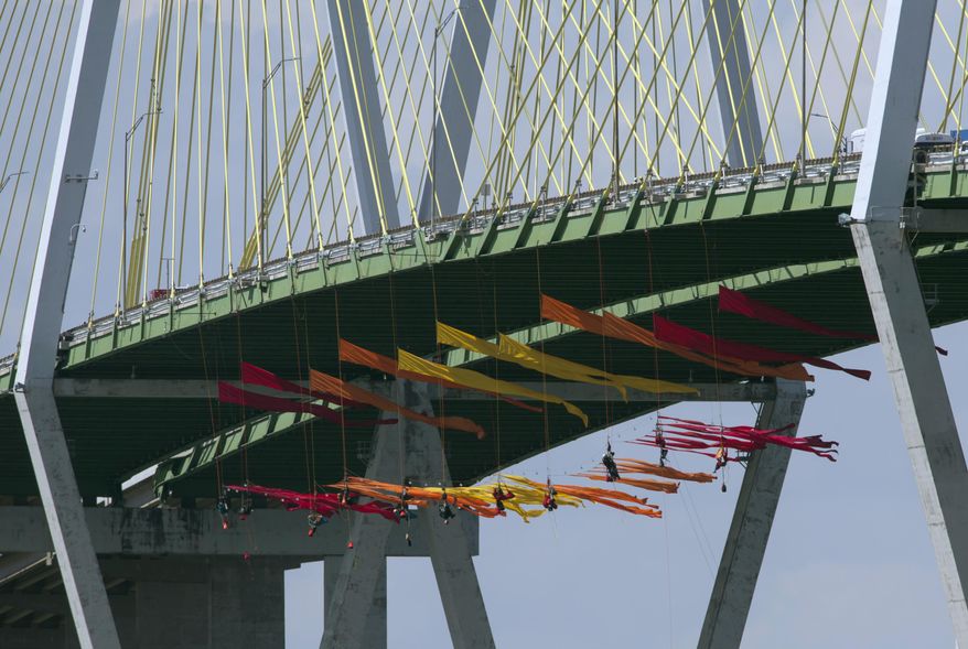 Greenpeace USA protesters dangle from the Fred Hartman Bridge Thursday, Sept. 12, 2019, in Baytown, Texas. A portion of the Houston Ship Channel has closed after about a dozen Greenpeace USA activists protesting the use of fossil fuels suspended themselves from a bridge ahead of a Democratic presidential debate.( Yi-Chin Lee/Houston Chronicle via AP)