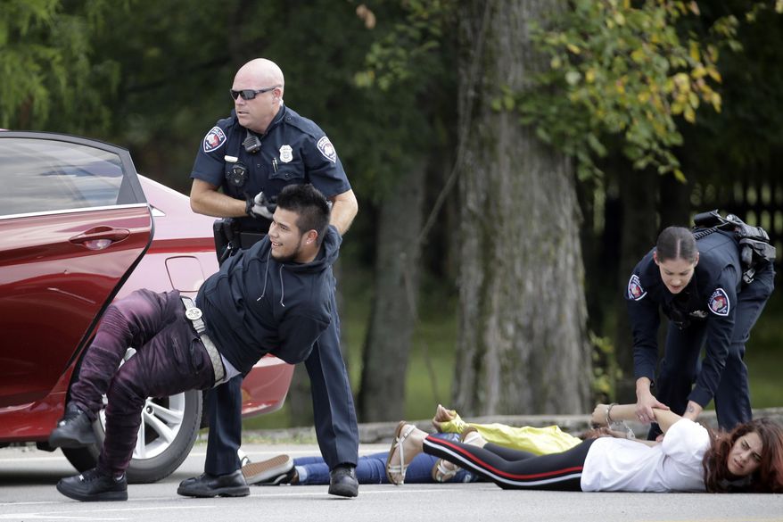 Police officers make arrests after stopping a car Thursday, Sept. 12, 2019, in Nolensville, Tenn. Six people have been taken into custody in connection with a series of armed robberies in Brentwood and Nolensville. (AP Photo/Mark Humphrey)