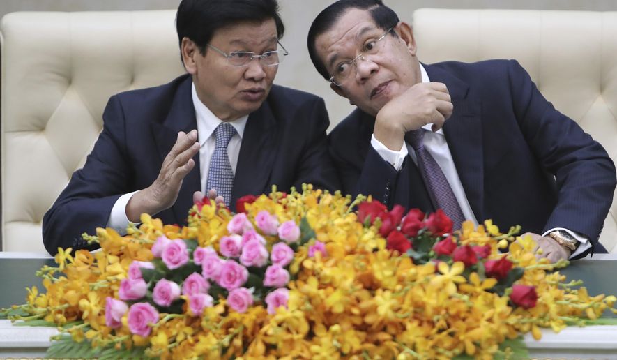 Cambodian Prime Minister Hun Sen, right, talks with his Laos counterpart Thonloun Sisoulith, left, as they witness to a signing ceremony in Phnom Penh, Cambodia, Thursday, Sept. 12, 2019. Thonloun Sisoulith is on his two-day official visit to Cambodia. (AP Photo/Heng Sinith)