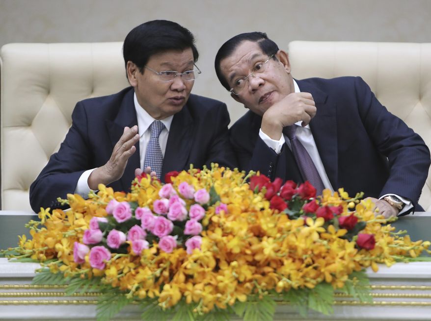 Cambodian Prime Minister Hun Sen, right, talks with his Laos counterpart Thonloun Sisoulith, left, as they witness to a signing ceremony in Phnom Penh, Cambodia, Thursday, Sept. 12, 2019. Thonloun Sisoulith is on his two-day official visit to Cambodia. (AP Photo/Heng Sinith)