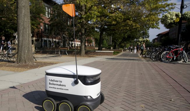 A Starship Technologies robot drives through campus delivering food at Purdue University, Thursday, Sept. 12, 2019, in West Lafayette, Ind. For the past month, Purdue students have seen little robots making their way across campus, down sidewalks and across streets. They&#x27;re white and cooler-sized, with six little wheels and a long pole with an orange flag alerting those around of their presence. (Nikos Frazier/Journal &amp; Courier via AP)