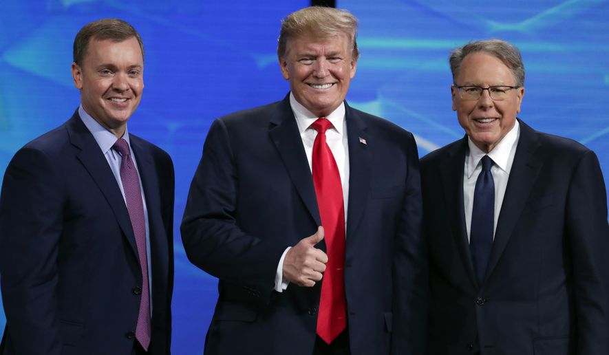 FILE - In this Friday, April 26, 2019 file photo, President Donald Trump poses with NRA-ILA Executive Director Chris Cox, left, and executive Vice President Wayne LaPierre before speaking at the National Rifle Association Institute for Legislative Action Leadership Forum in Lucas Oil Stadium in Indianapolis. The National Rifle Association is meeting in the shadows of Congress as its leaders remain under fire for spending and its operations. Amid the turmoil, lawmakers are considering steps to stem gun violence, including proposals long opposed by the NRA. (AP Photo/Michael Conroy, File)