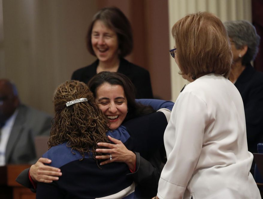 Assemblywoman Monique Limon, D-Santa Barbara, center, hugs state Sen. Holly Mitchell, D-Los Angeles, left, after her bill, AB539, to cap interest rates for consumer loans was approved by the Senate in Sacramento, Calif., Friday, Sept. 13, 2019. Mitchell carried the bill in the Senate for Limon, that now needs approval from the Assembly. (AP Photo/Rich Pedroncelli)