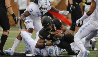 Wake Forest quarterback Jamie Newman (12) rushes for a touchdown over North Carolina defensive back Myles Wolfolk (11) during the first half of an NCAA college football game in Winston-Salem, N.C., Friday, Sept. 13, 2019. (AP Photo/Nell Redmond)