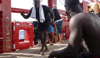 A man dances as another plays the drums aboard the Ocean Viking in the Mediterranean Sea, Thursday, Sept. 12, 2019. Eighty-two rescued migrants remain on board the humanitarian rescue ship waiting for a European country to give them permission to disembark. (AP Photo/Renata Brito)