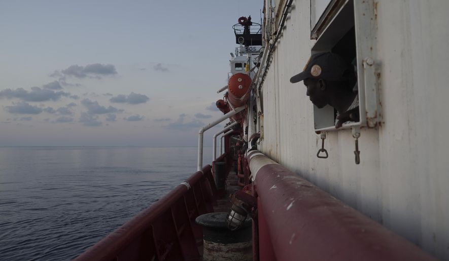 A rescued migrant looks at the horizon from inside the men's shelter aboard the Ocean Viking in the Mediterranean Sea near the island of Lampedusa, Italy, Saturday, Sept. 14, 2019. Italy allowed a charity rescue ship to sail Saturday to a tiny southern island so the 82 migrants aboard could be transferred to shore, but the Italian foreign minister cautioned against interpreting the OK as a sign the new government is easing a crackdown on humanitarian vessels. (AP Photo/Renata Brito)