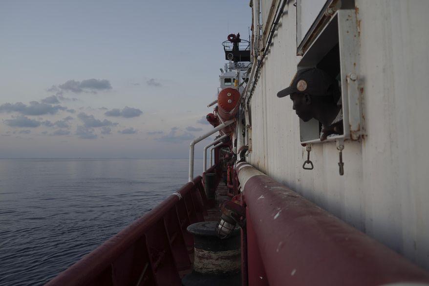 A rescued migrant looks at the horizon from inside the men's shelter aboard the Ocean Viking in the Mediterranean Sea near the island of Lampedusa, Italy, Saturday, Sept. 14, 2019. Italy allowed a charity rescue ship to sail Saturday to a tiny southern island so the 82 migrants aboard could be transferred to shore, but the Italian foreign minister cautioned against interpreting the OK as a sign the new government is easing a crackdown on humanitarian vessels. (AP Photo/Renata Brito)