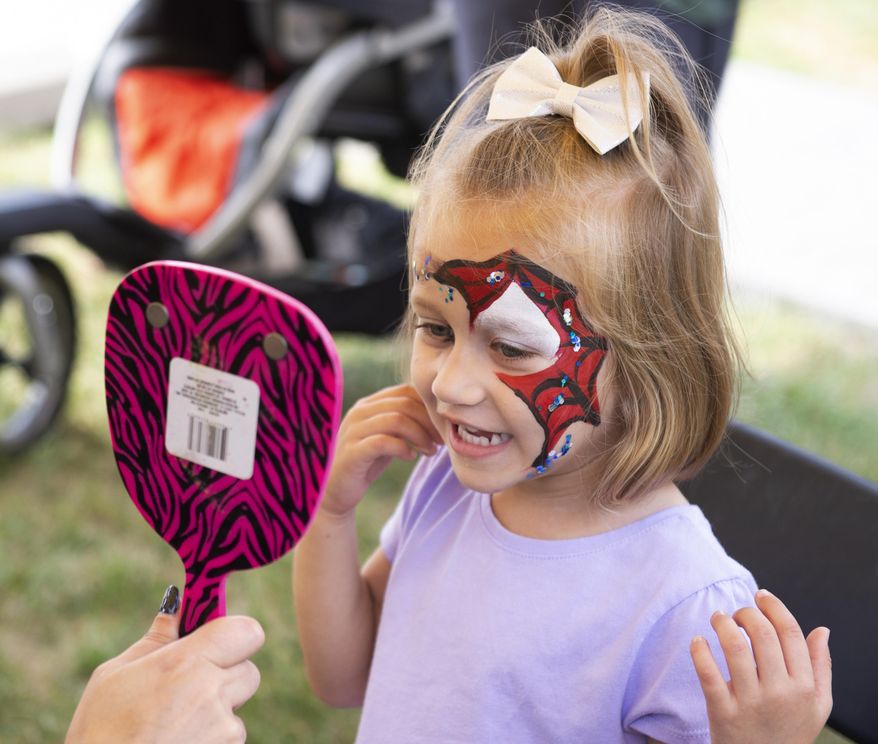 In this Saturday, Sept. 7, 2019 photo, Charlie Winter checks out her new face paint in a mirror during Applefest at Christ United Methodist in Lincoln, Neb. (Emily Janey/Lincoln Journal Star via AP)