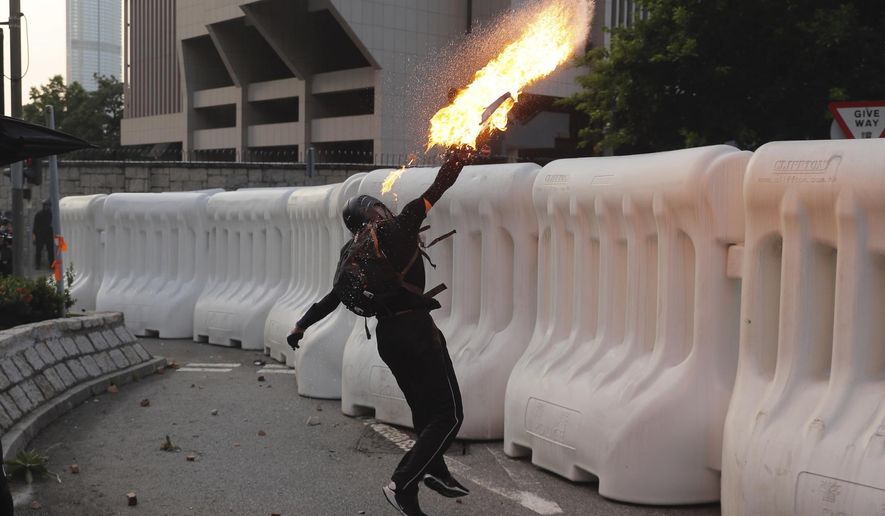 An anti-government protester throws a Molotov cocktail during a demonstration near Central Government Complex in Hong Kong, Sunday, Sept. 15, 2019. Police fired a water cannon and tear gas at protesters who lobbed Molotov cocktails outside the Hong Kong government office complex Sunday, as violence flared anew after thousands of pro-democracy supporters marched through downtown in defiance of a police ban. (AP Photo/Kin Cheung)