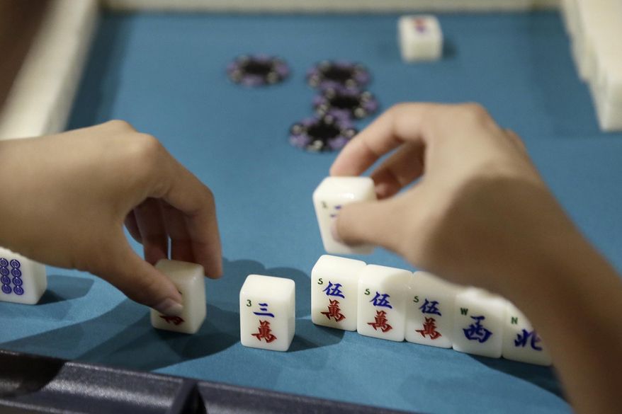 In this July 17, 2018 photo, Inquirer writer Bethany Ao makes a move while playing Mahjong, with The Philly Mah-Jawng Club, at ThirstyDice in the Spring Garden section of Philadelphia. (Elizabeth Robertson/The Philadelphia Inquirer via AP)